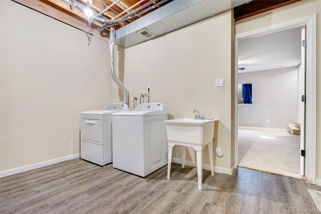 clothes washing area featuring laundry area, baseboards, light wood finished floors, and washer and clothes dryer