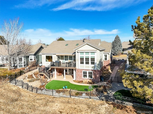 rear view of property featuring brick siding, a fenced backyard, stairway, and a patio