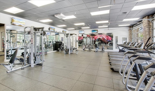 workout area featuring a drop ceiling and a healthy amount of sunlight