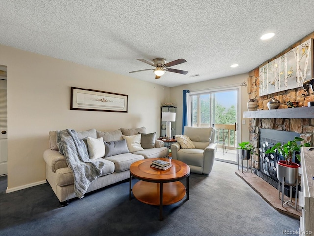 carpeted living area with ceiling fan, a textured ceiling, recessed lighting, a stone fireplace, and baseboards