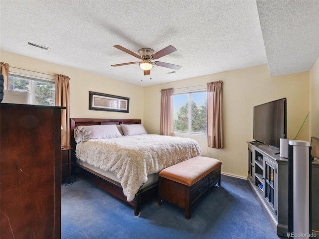 bedroom with dark colored carpet, a textured ceiling, a ceiling fan, and baseboards