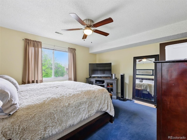 bedroom with dark carpet, ceiling fan, and a textured ceiling