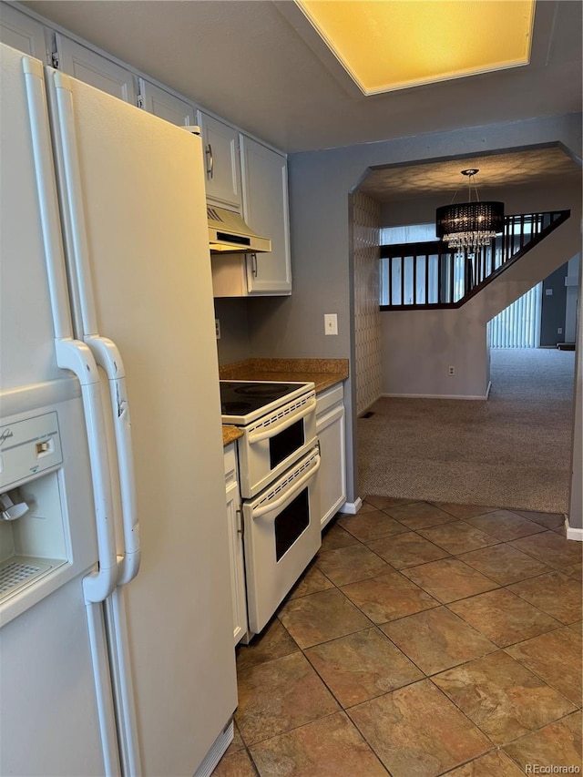 kitchen featuring white appliances, white cabinetry, an inviting chandelier, dark colored carpet, and decorative light fixtures