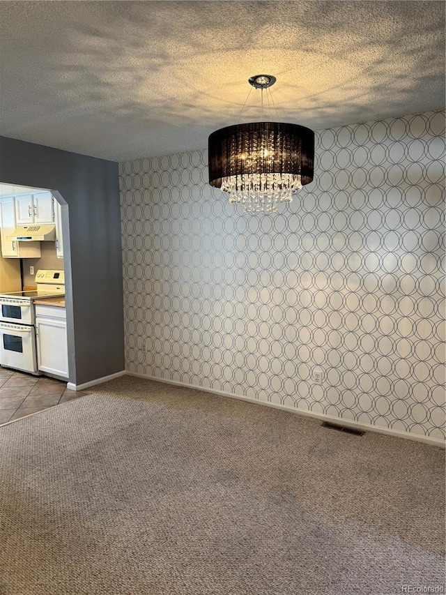 unfurnished dining area featuring carpet floors, an inviting chandelier, and a textured ceiling