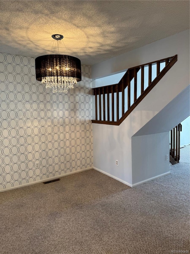 unfurnished dining area with carpet floors, a textured ceiling, and a chandelier