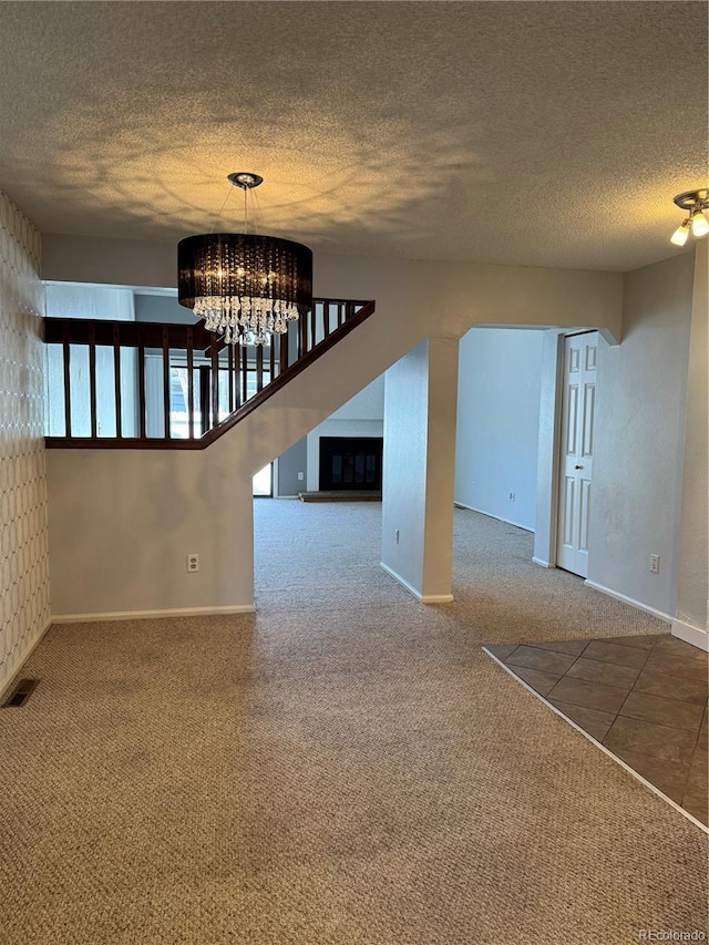 spare room with an inviting chandelier, a textured ceiling, and carpet flooring