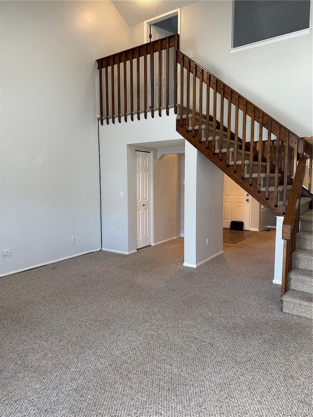 staircase with a towering ceiling and carpet