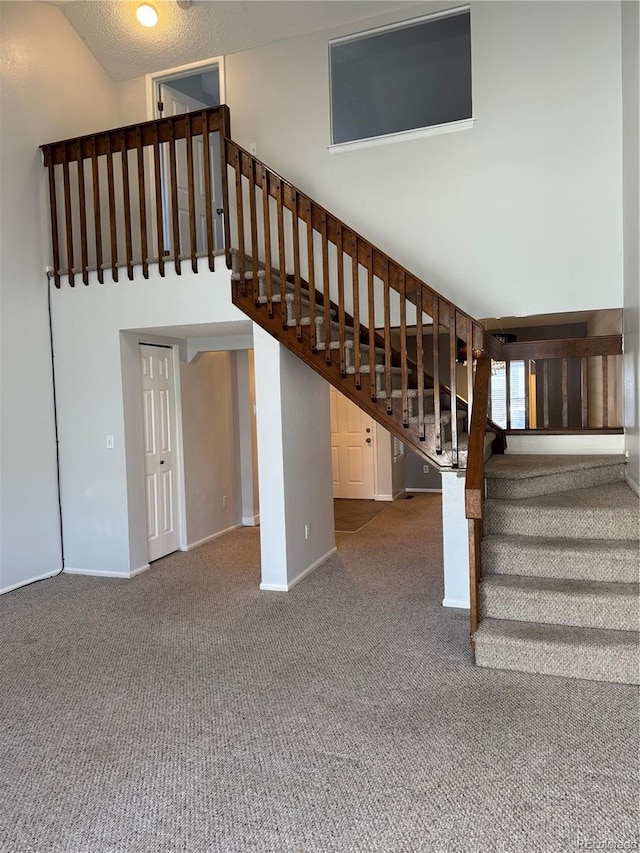 staircase featuring a high ceiling and carpet flooring