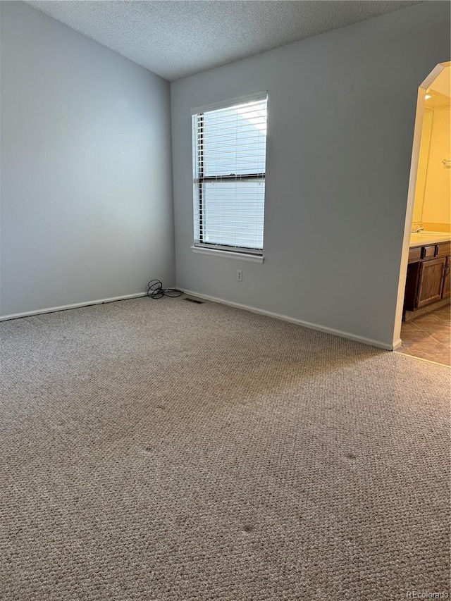 carpeted spare room with a textured ceiling