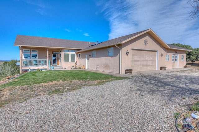 single story home with covered porch, a garage, and a front yard