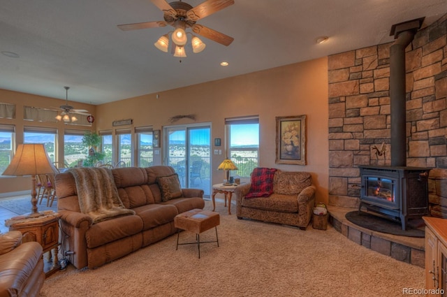 carpeted living room featuring ceiling fan and a wood stove