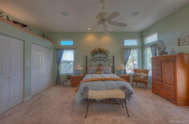 bedroom with multiple windows, light colored carpet, and ceiling fan