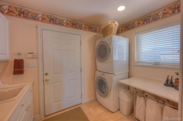 washroom with cabinets, light tile patterned floors, sink, and stacked washer and clothes dryer