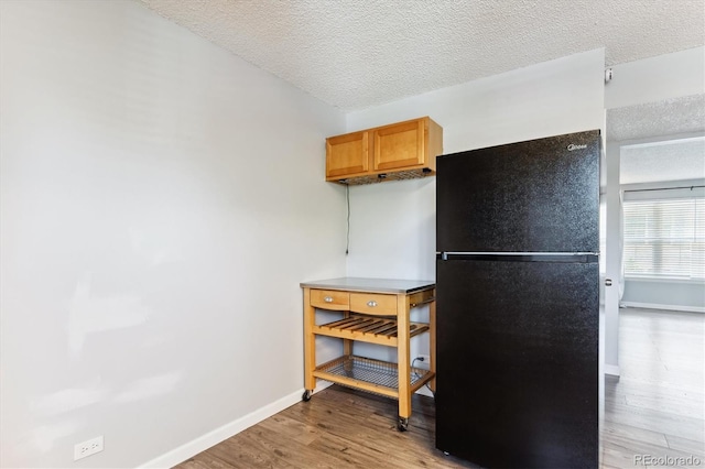 kitchen featuring black fridge, a textured ceiling, and light hardwood / wood-style floors