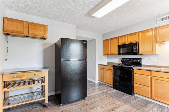 kitchen featuring a textured ceiling, light wood-type flooring, and black appliances