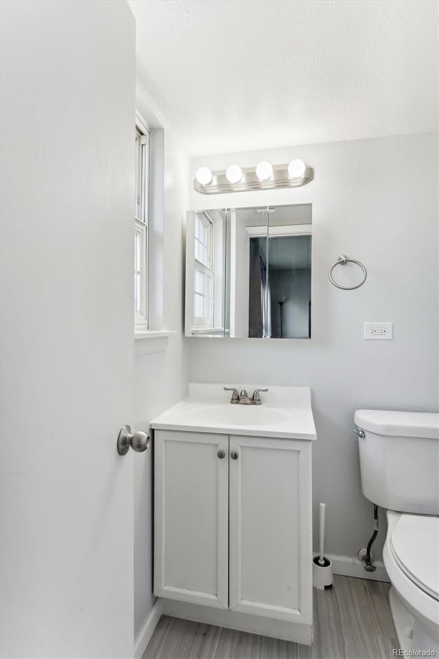 bathroom with hardwood / wood-style flooring, vanity, and toilet