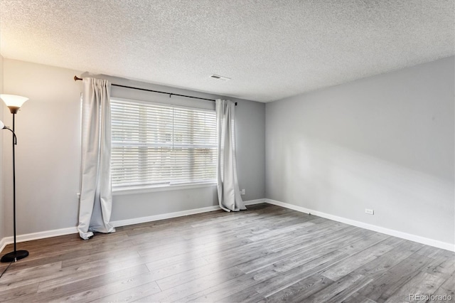 spare room featuring hardwood / wood-style floors and a textured ceiling