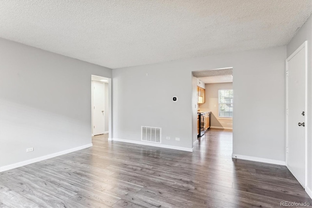 empty room with a textured ceiling and dark wood-type flooring