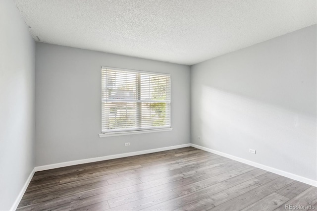 spare room featuring hardwood / wood-style floors and a textured ceiling