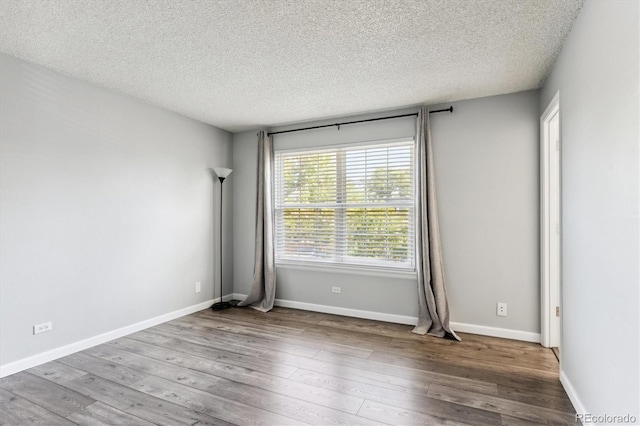 empty room with hardwood / wood-style flooring and a textured ceiling