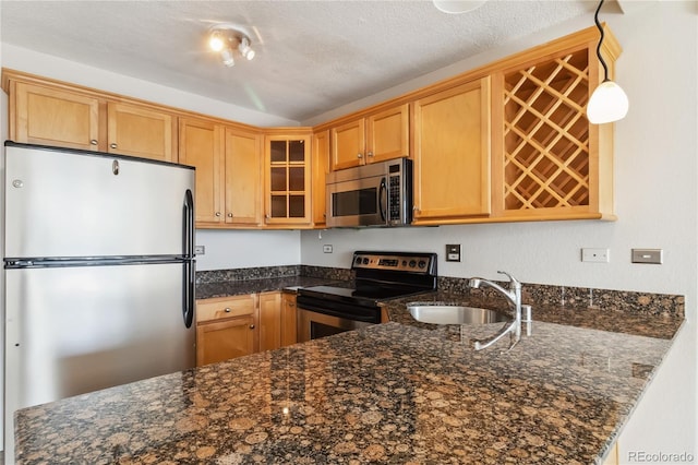 kitchen featuring appliances with stainless steel finishes, dark stone counters, glass insert cabinets, and a sink