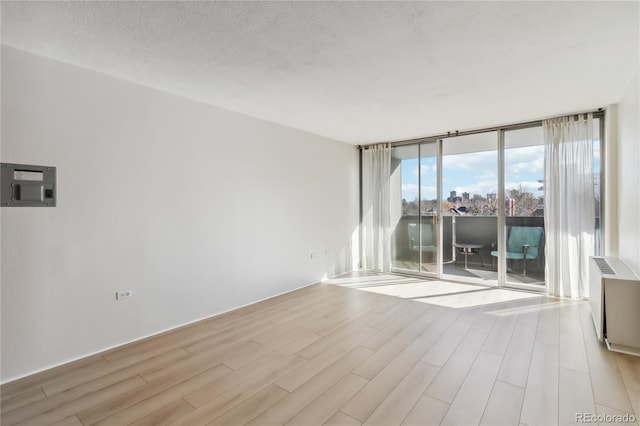 spare room with floor to ceiling windows, wood finished floors, and a textured ceiling