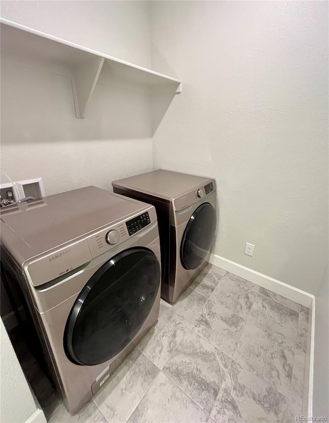 washroom featuring laundry area, washing machine and clothes dryer, and baseboards