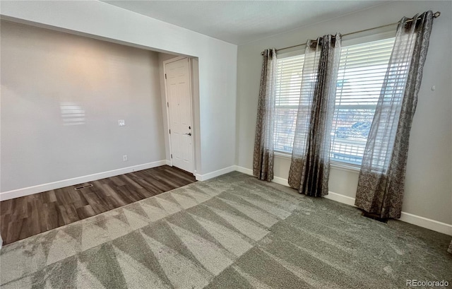 spare room with carpet, baseboards, and wood finished floors