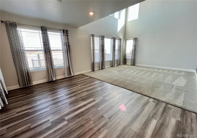 unfurnished room with a high ceiling, recessed lighting, wood finished floors, and baseboards