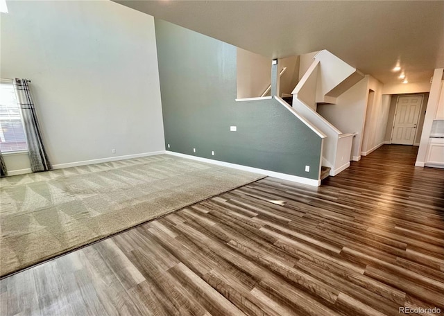 unfurnished living room featuring stairway, baseboards, and wood finished floors