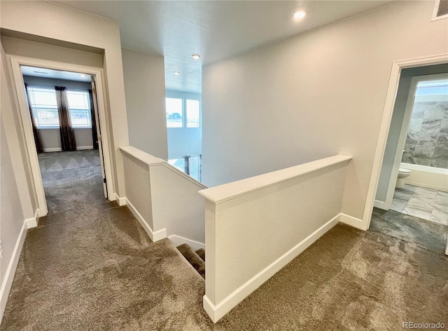 corridor with visible vents, baseboards, carpet flooring, and an upstairs landing