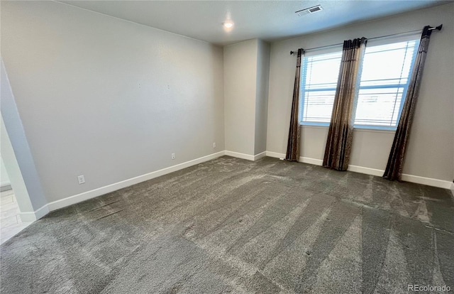 carpeted spare room with visible vents and baseboards