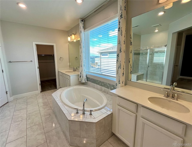 bathroom with a garden tub, two vanities, a spacious closet, a stall shower, and a sink