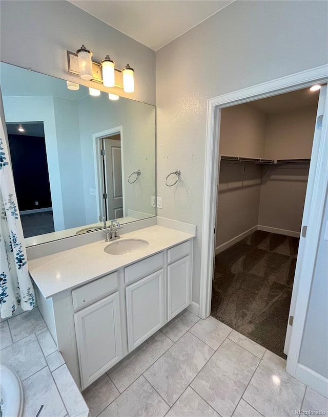 bathroom featuring a walk in closet, vanity, and baseboards