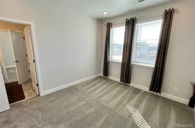 spare room with carpet floors, visible vents, and baseboards