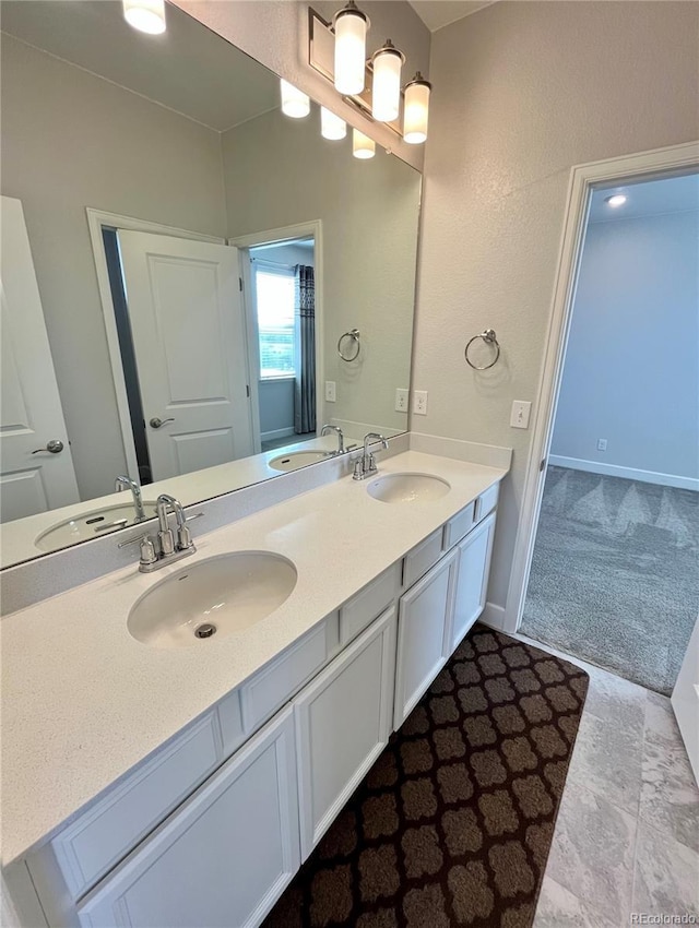 full bathroom featuring double vanity, baseboards, and a sink