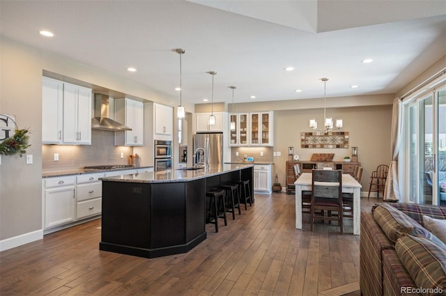 350 Andromeda Ln, Castle Rock, CO 80108 - kitchen with wall chimney exhaust hood, appliances with stainless steel finishes, a kitchen breakfast bar, dark wood-type flooring, and recessed lighting