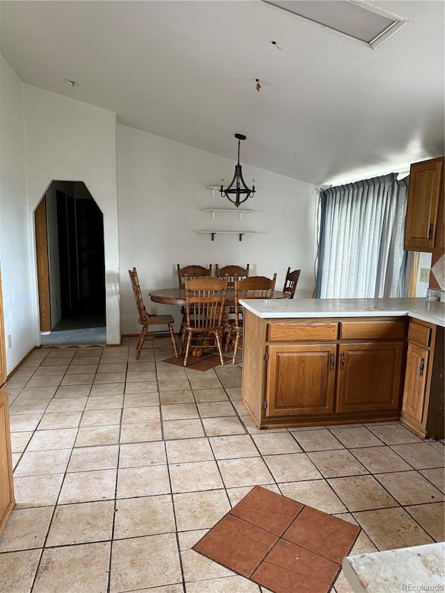 554 E Pleasant Ave, Byers, CO 80103 - kitchen featuring a peninsula, lofted ceiling, light countertops, brown cabinetry, and pendant lighting