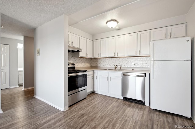 kitchen with sink, stainless steel appliances, tasteful backsplash, and white cabinetry