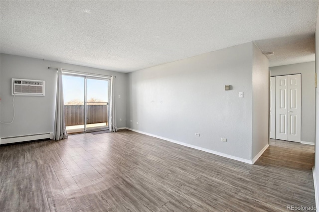 empty room with a wall mounted AC, a baseboard radiator, a textured ceiling, and hardwood / wood-style floors