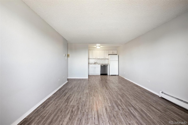 unfurnished living room featuring a baseboard heating unit, a textured ceiling, sink, and dark wood-type flooring