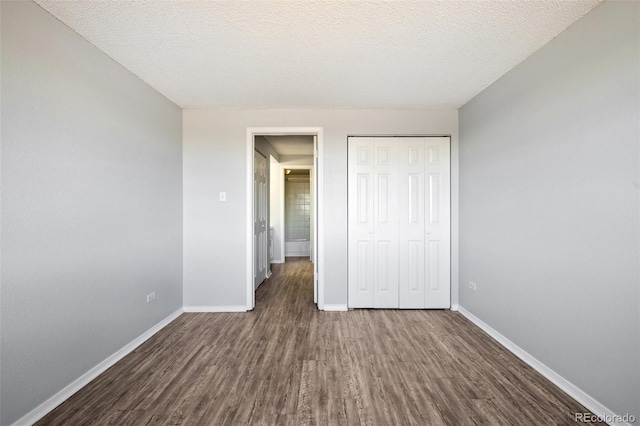 unfurnished bedroom featuring a closet, a textured ceiling, and dark wood-type flooring