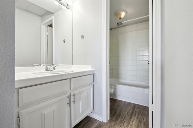 full bathroom featuring tiled shower / bath, hardwood / wood-style floors, vanity, and toilet