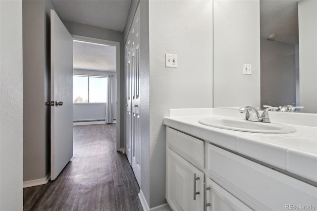 bathroom featuring a textured ceiling, vanity, a baseboard radiator, and hardwood / wood-style floors