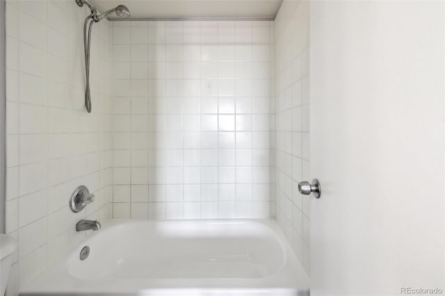 bathroom with toilet and tiled shower / bath