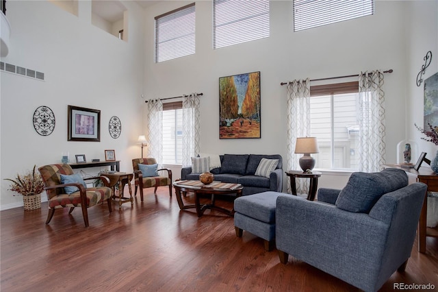 living room with a towering ceiling and dark hardwood / wood-style flooring