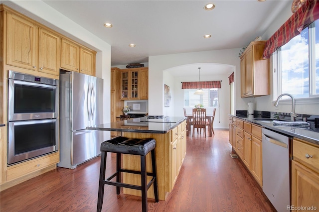 kitchen featuring sink, a center island, dark hardwood / wood-style flooring, a breakfast bar, and appliances with stainless steel finishes