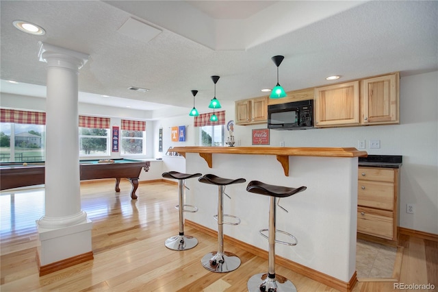 kitchen featuring hanging light fixtures, billiards, light brown cabinetry, a breakfast bar, and light wood-type flooring