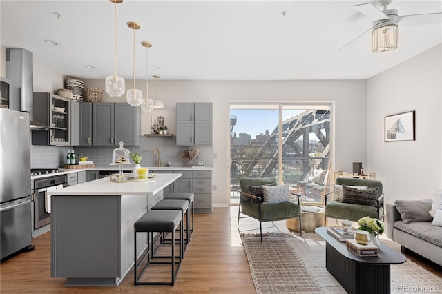 kitchen with appliances with stainless steel finishes, a kitchen breakfast bar, hanging light fixtures, and a kitchen island