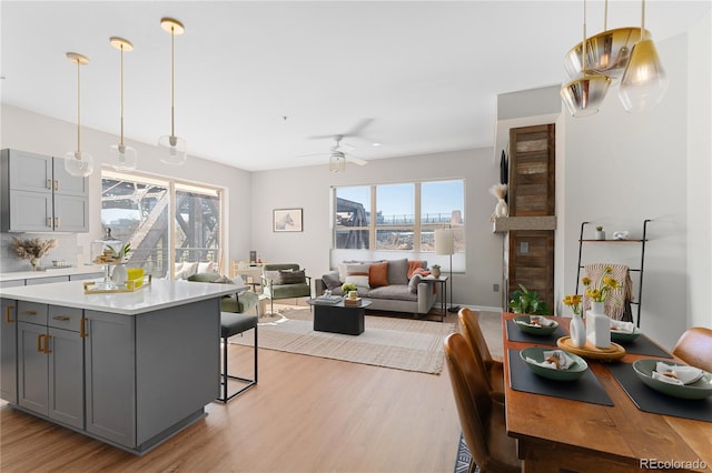 kitchen with a breakfast bar area, light hardwood / wood-style floors, hanging light fixtures, and gray cabinetry